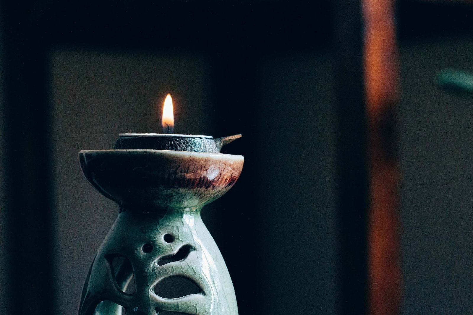 A candle burning in a green ceramic holder